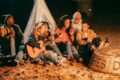 group of friends sitting on beach sand