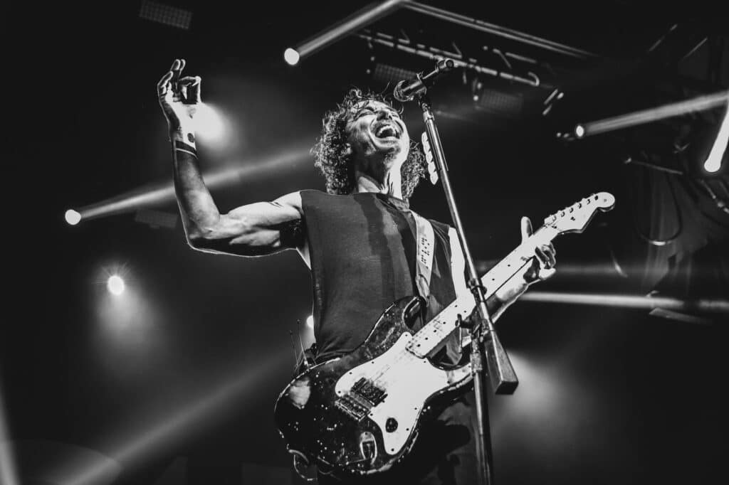 grayscale photo of man playing electric guitar performing on stage