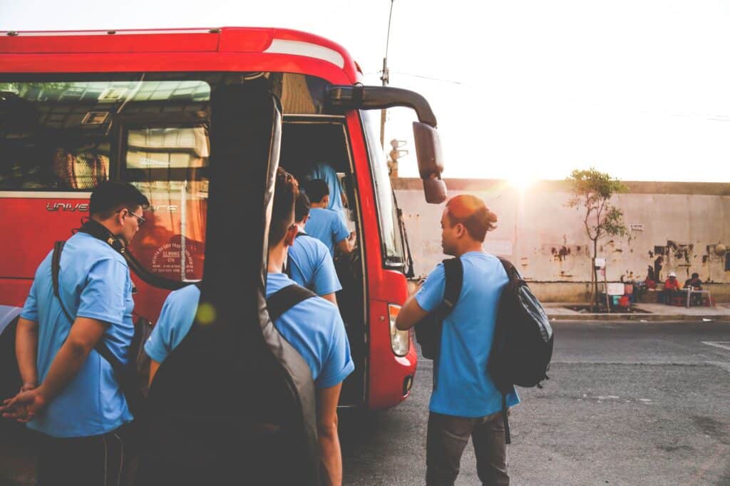 group of men wearing blue shirts about to enter red bus