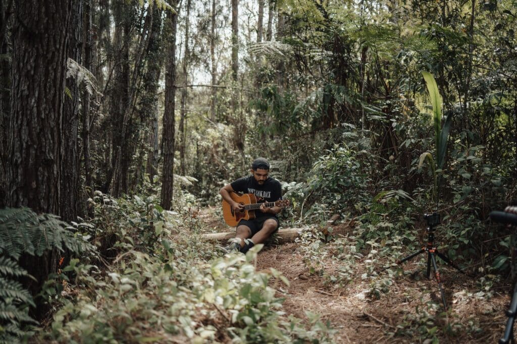 man playing guitar in the woods