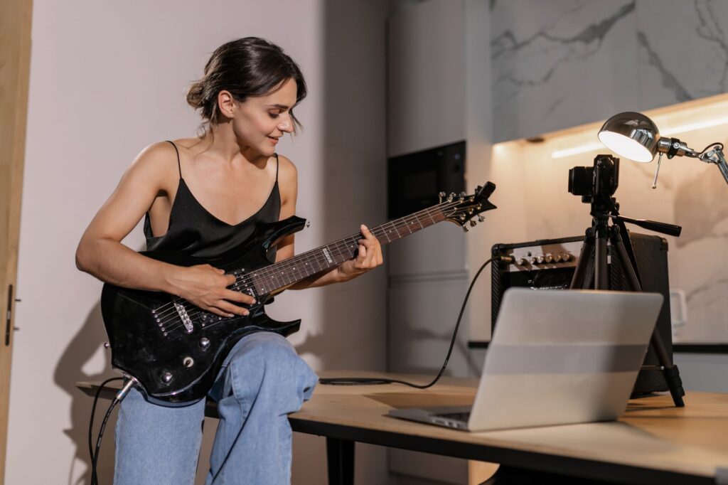 woman in black spaghetti strap top playing electric guitar